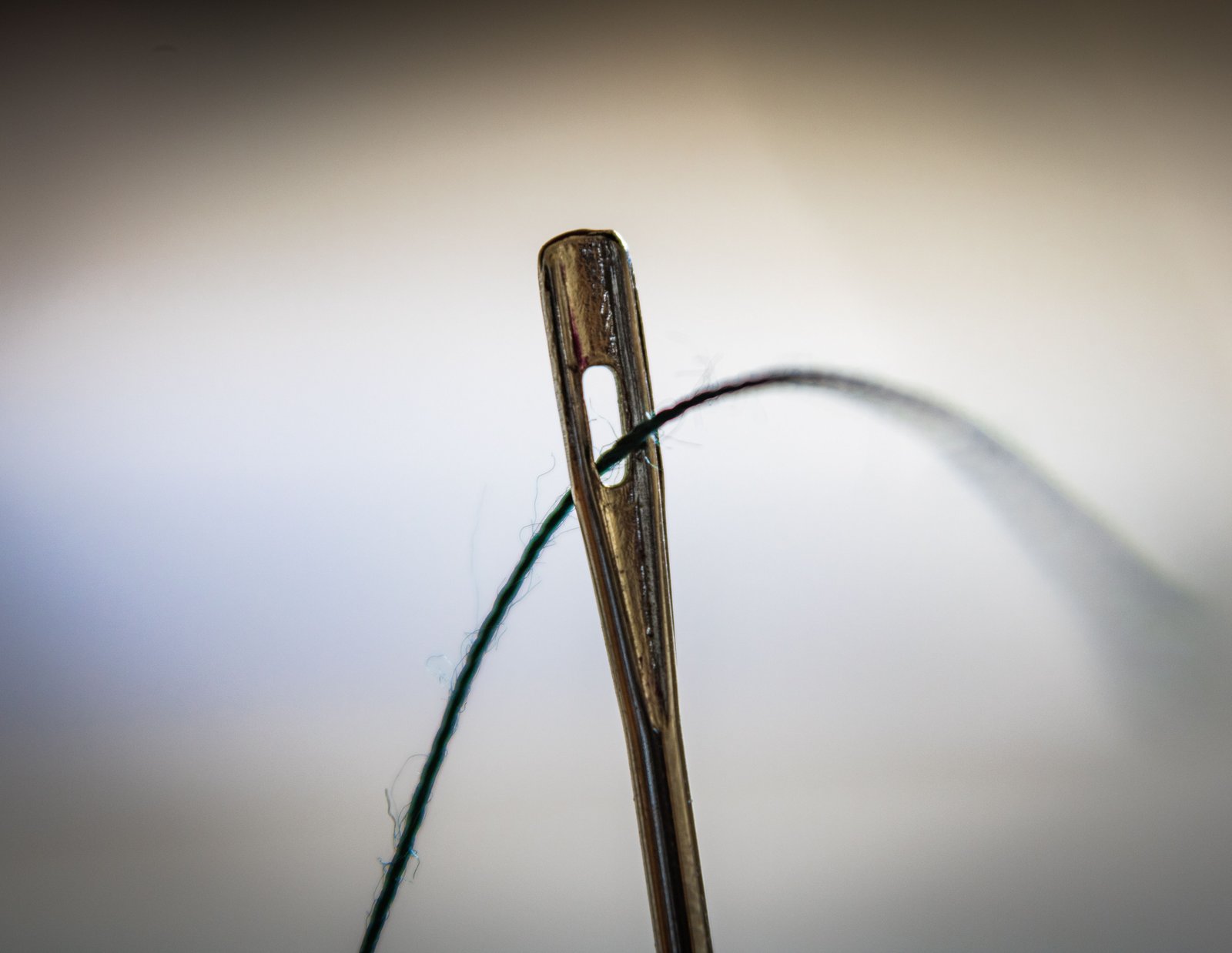 Hand-stitched garment repair, needle and thread detail