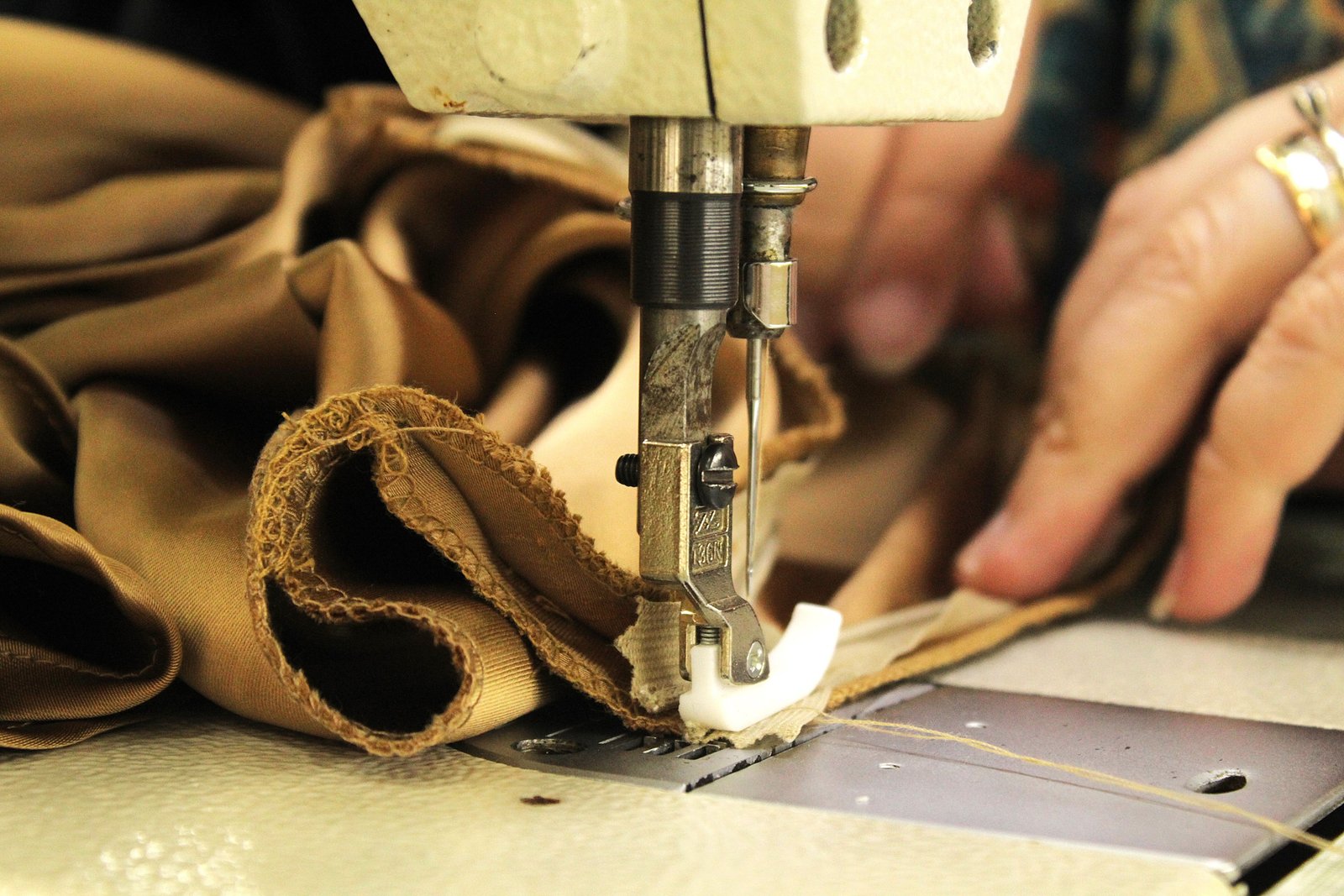 Hands guiding fabric through a sewing machine during a garment repair